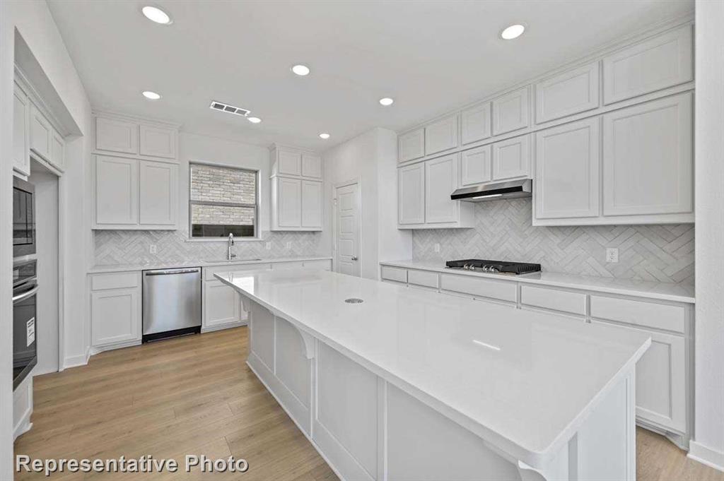 a kitchen with stainless steel appliances sink refrigerator and white cabinets