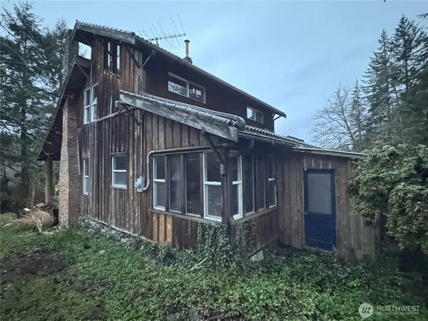 a view of wooden house with a small yard and wooden fence
