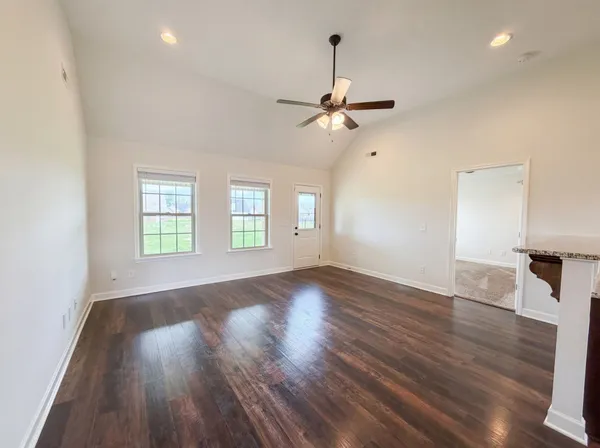 a view of an empty room with a window and wooden floor