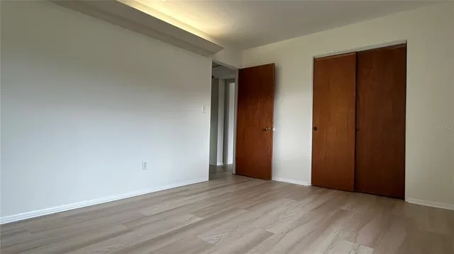an empty room with wooden floor and closet