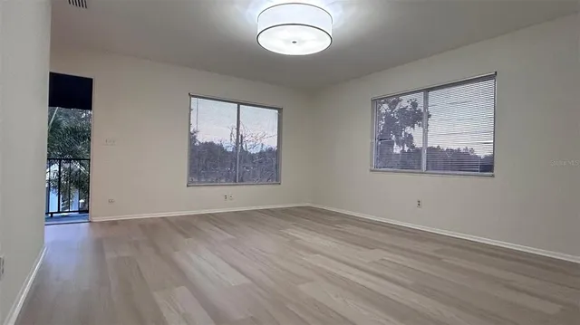 an empty room with wooden floor mirror and windows