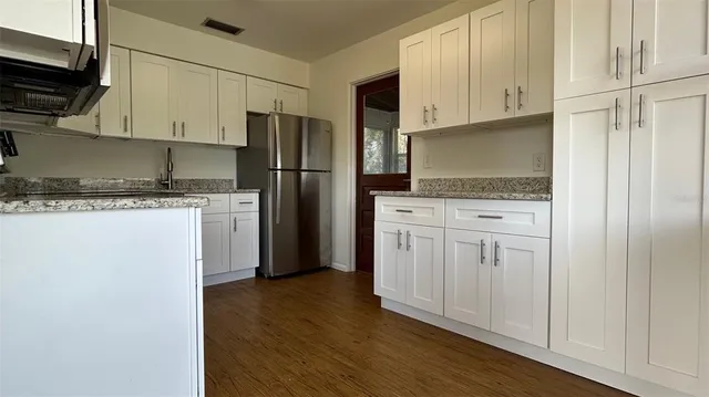 a kitchen with granite countertop white cabinets and refrigerator