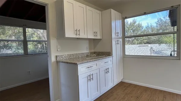 a kitchen with granite countertop white cabinets and a wooden floor
