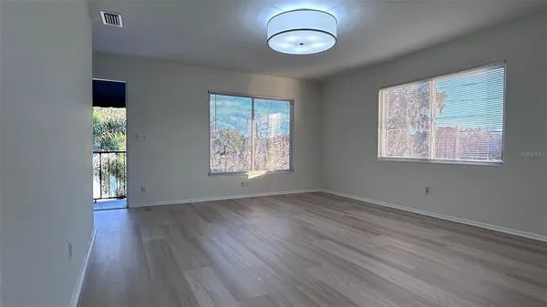 a view of an empty room with wooden floor and a window