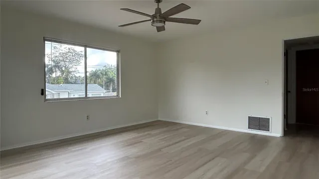 an empty room with wooden floor and windows