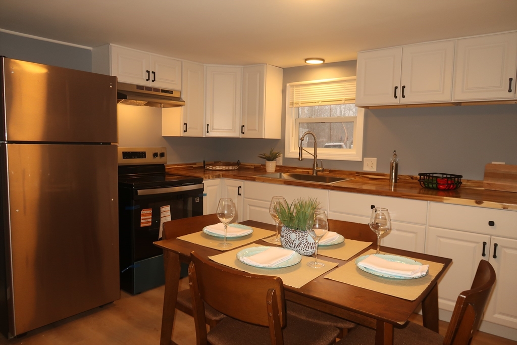 229 Miller Street, Unit 3G Ludlow, MA 01056 - Photo 2 of 15 a kitchen with stainless steel appliances granite countertop a sink a stove a refrigerator a dining table and chairs