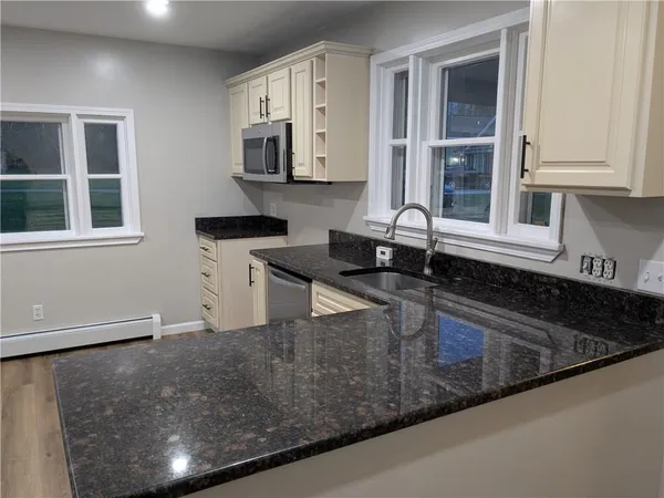 a kitchen with granite countertop a sink a stove and cabinets