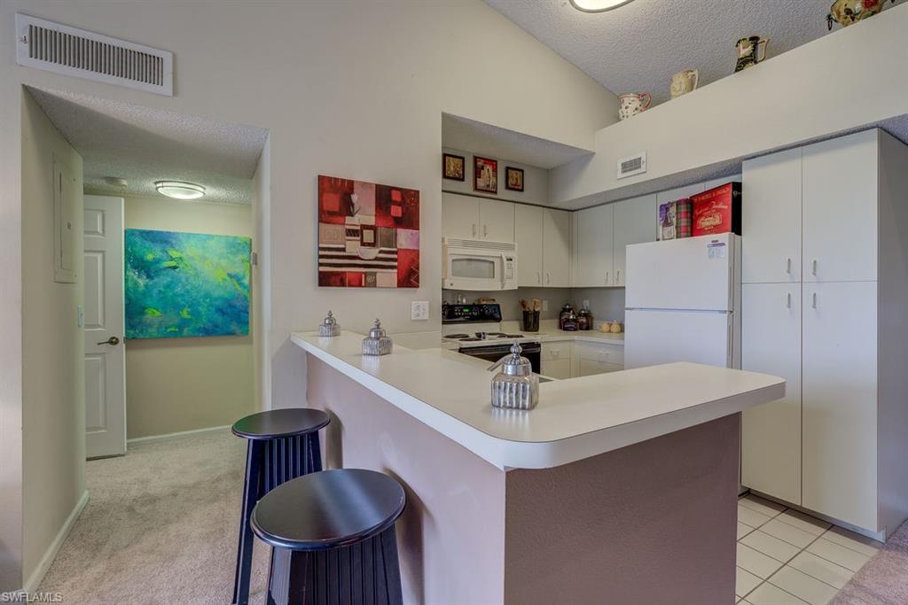 13545 Eagle Ridge Drive, Unit 827 Fort Myers, FL 33912 - Photo 14 of 27 a kitchen with a sink a stove and chairs