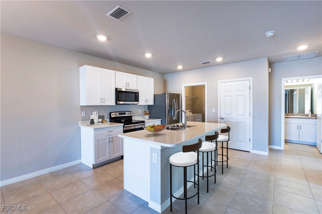 10749 Crossback Lane Lehigh Acres, FL 33974 - Photo 2 of 21 a large kitchen with kitchen island a sink table and chairs