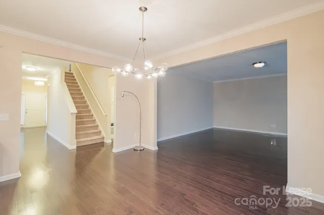 an empty room with wooden floor and staircase
