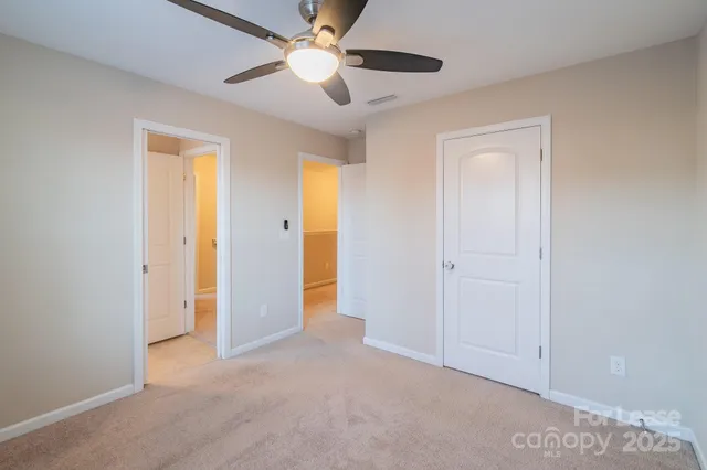 an empty room with closet and a ceiling fan