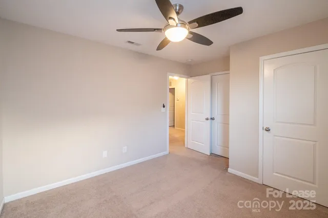 an empty room with closet and a ceiling fan