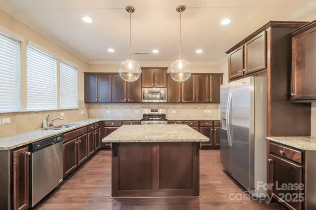 a kitchen with stainless steel appliances granite countertop a sink a stove a refrigerator and a center island