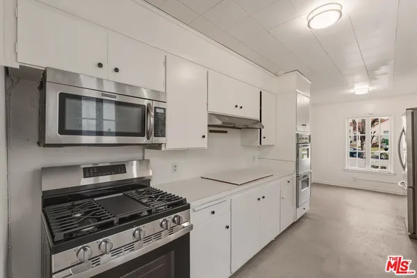 a kitchen with stainless steel appliances a white cabinet and a stove top oven