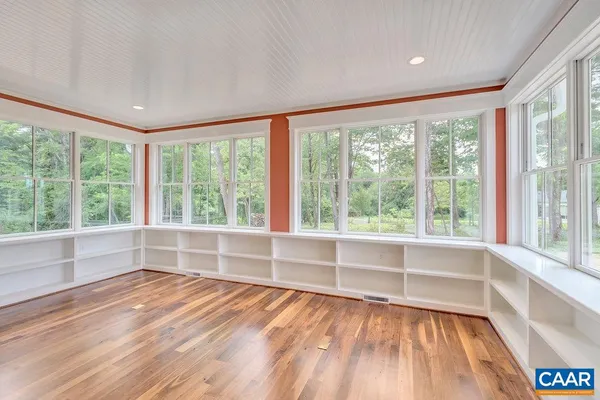 a view of empty room with wooden floor and fan