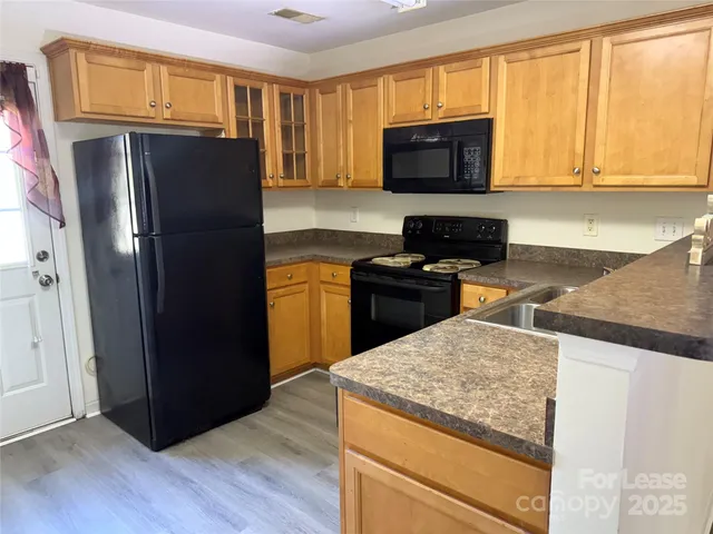 a kitchen with stainless steel appliances granite countertop a refrigerator a stove top oven a sink and dishwasher with wooden floor