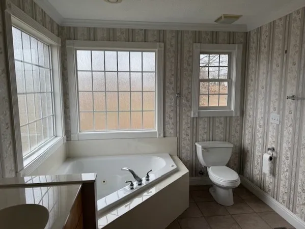a bathroom with a granite countertop toilet a sink and a window