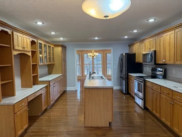 a large kitchen with stainless steel appliances granite countertop a large counter top a stove and a sink