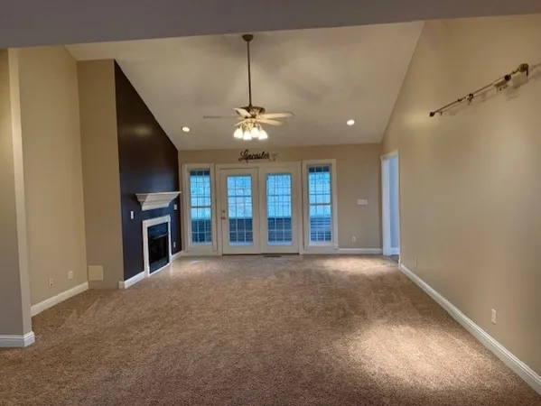 an empty room with chandelier fan and windows