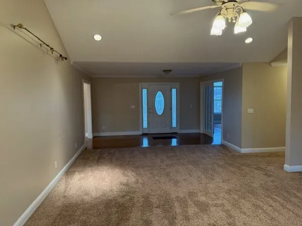 an empty room with a chandelier fan and windows