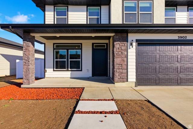 3902 West 825 North West Point, UT 84015 - Photo 7 of 49 Entrance to property with a porch, stone siding, concrete driveway, and an attached garage