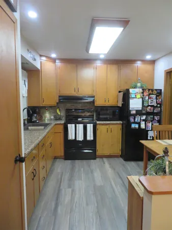 a kitchen with stainless steel appliances granite countertop a sink and a stove with wooden floor