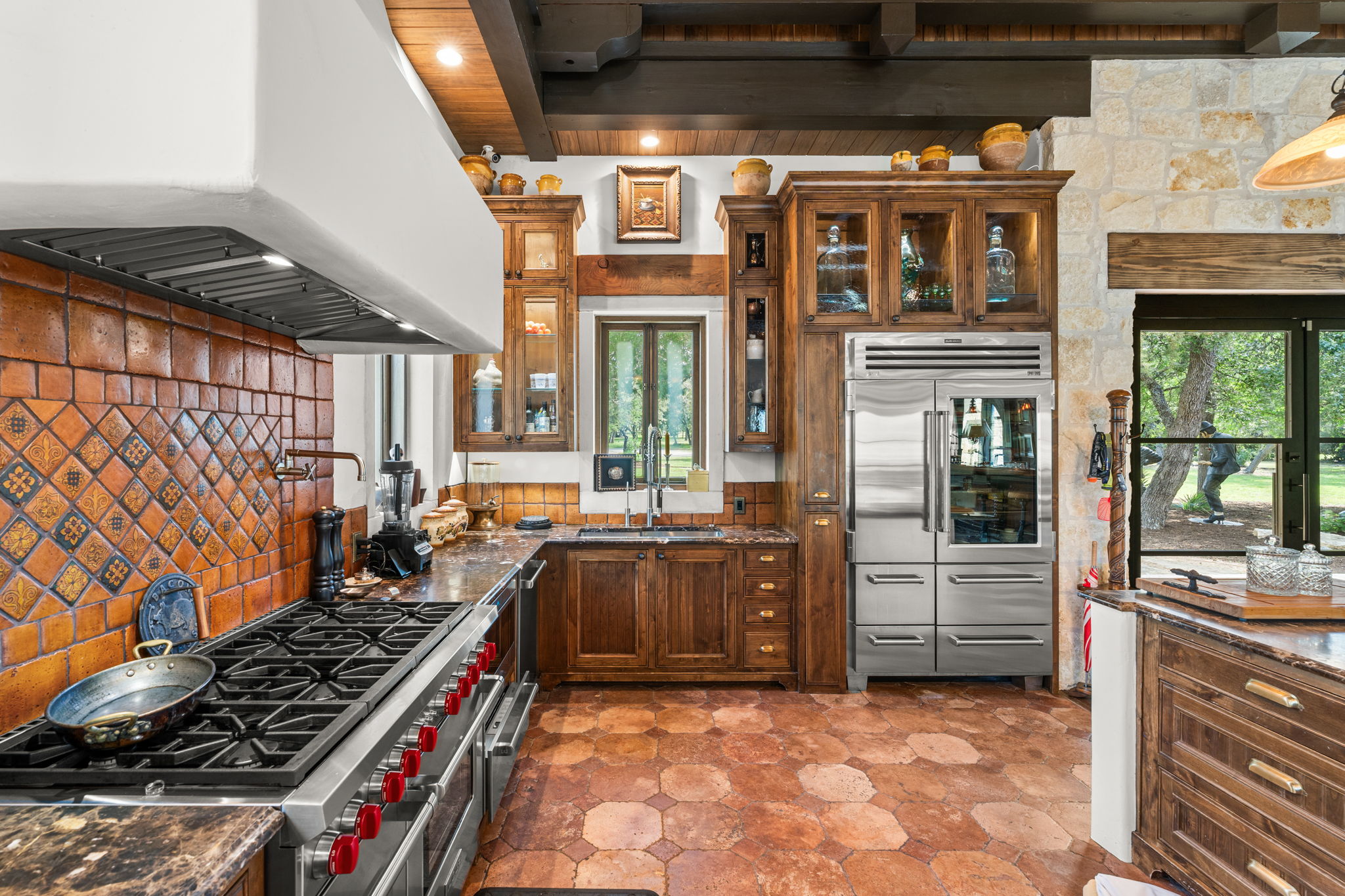 11941 Overlook Pass Austin, TX 78738 - Photo 40 of 40 Gourmet kitchen with professional-grade Wolfe range, Sub-zero refrigerator, custom wood cabinetry, unique terracotta tile flooring, and stone accent wall