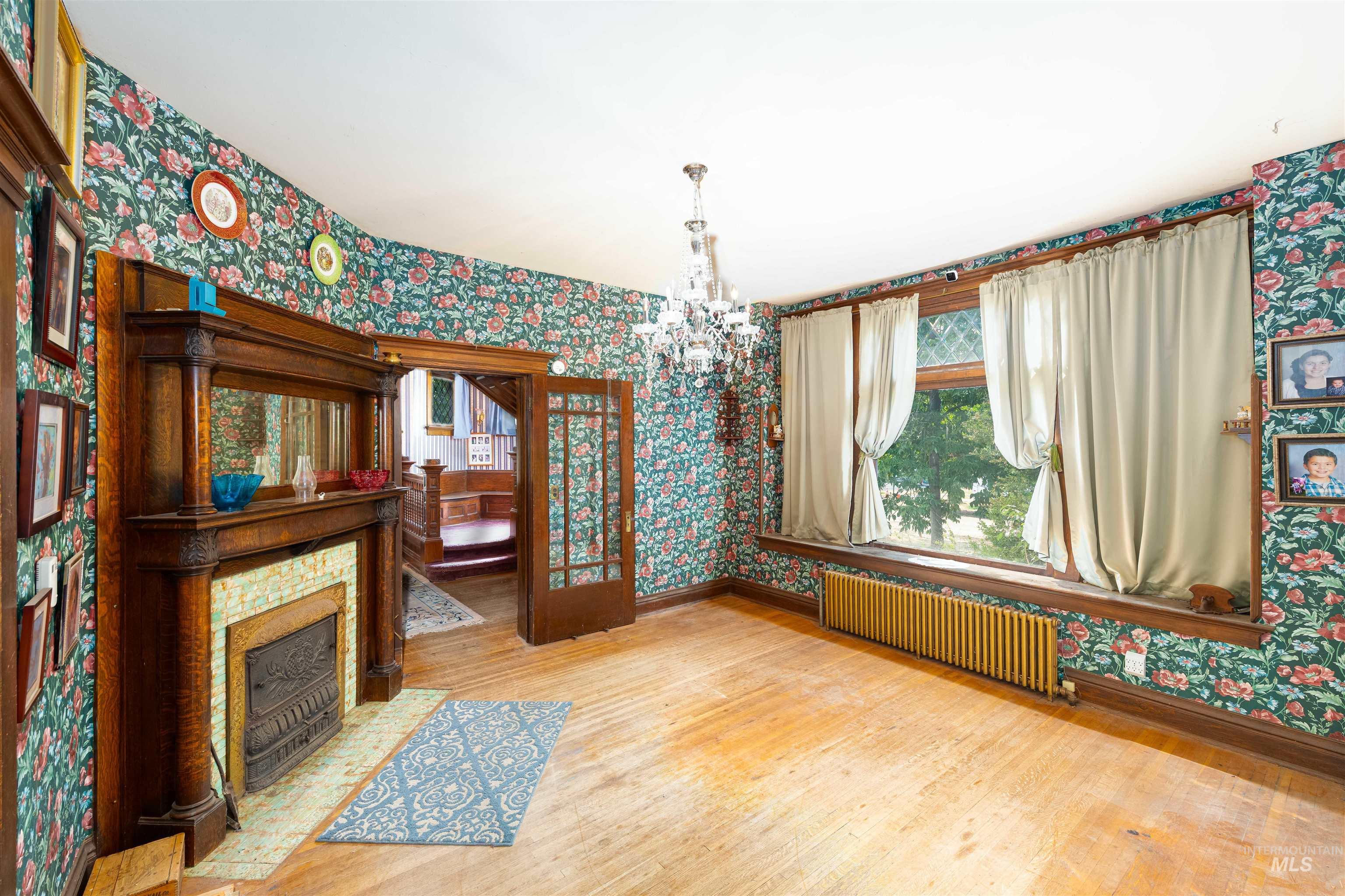 507 7th Avenue Lewiston, ID 83501 - Photo 13 of 30 Unfurnished dining area featuring wallpapered walls, light wood-type flooring, a chandelier, and radiator