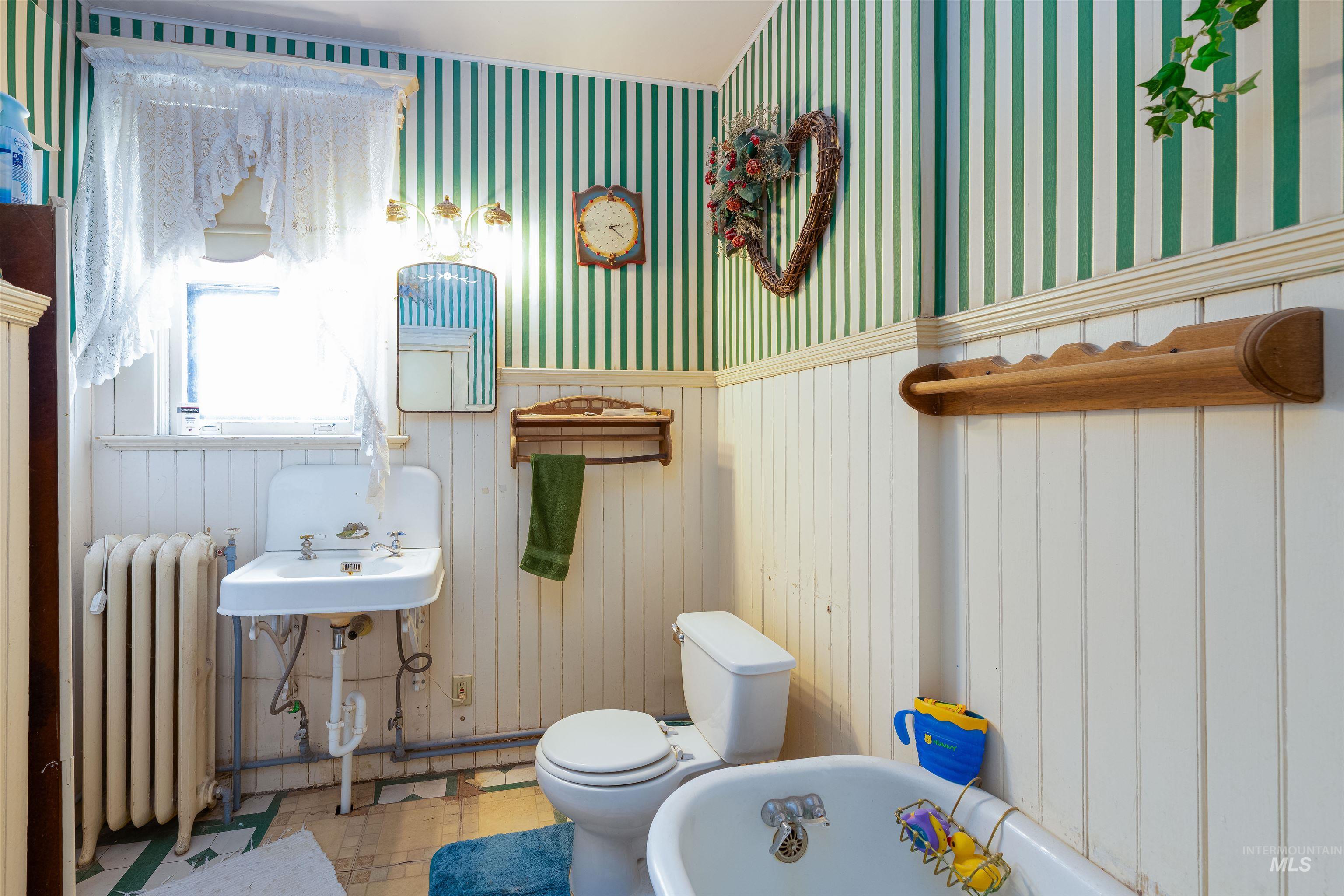507 7th Avenue Lewiston, ID 83501 - Photo 22 of 30 Bathroom with radiator heating unit, a freestanding tub, wallpapered walls, a wainscoted wall, and tile patterned floors