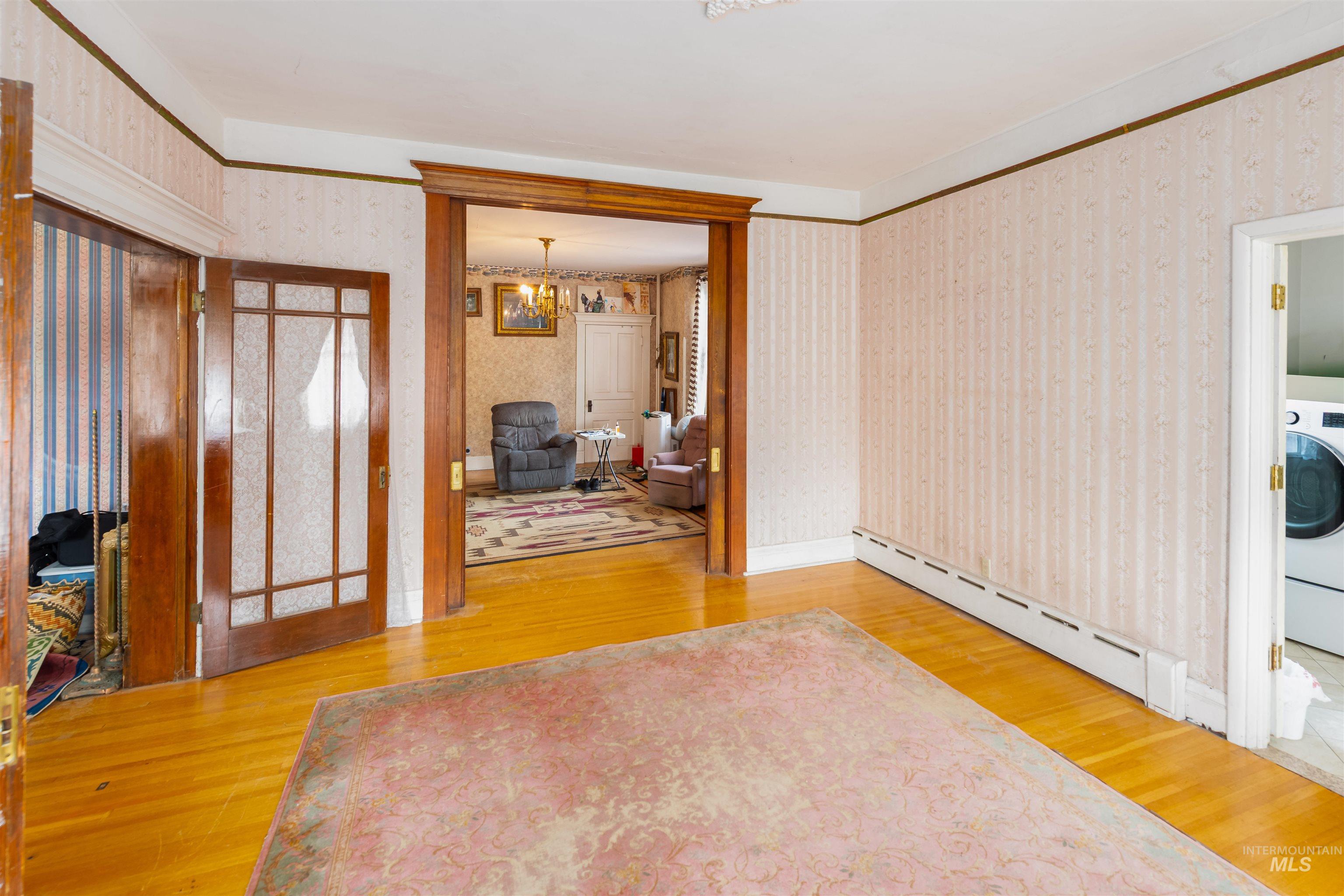 507 7th Avenue Lewiston, ID 83501 - Photo 8 of 30 Foyer entrance featuring a baseboard radiator, light wood-style floors, washer / dryer, wallpapered walls, and a chandelier
