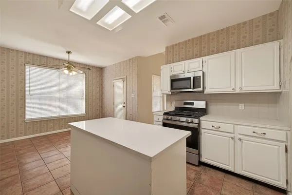 a kitchen with stainless steel appliances granite countertop a stove a sink and a microwave