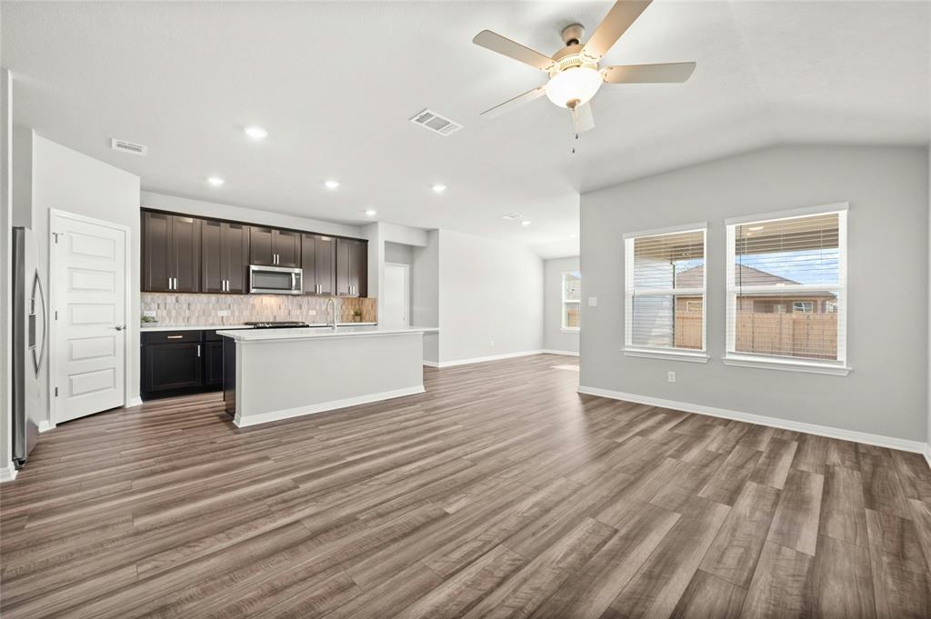 2805 Moyer Lane Round Rock, TX 78665 - Photo 25 of 25 a large kitchen with kitchen island a stove a refrigerator a sink dishwasher with a cabinets and wooden floor next to a window