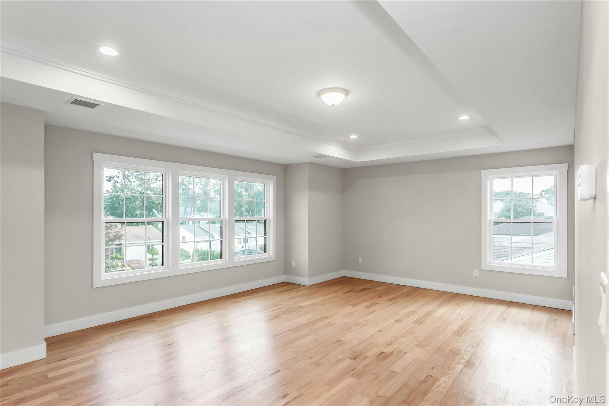 8 Sebree Place Plainview, NY 11803 - Photo 16 of 26 Empty room with light wood-style floors, recessed lighting, and a raised ceiling