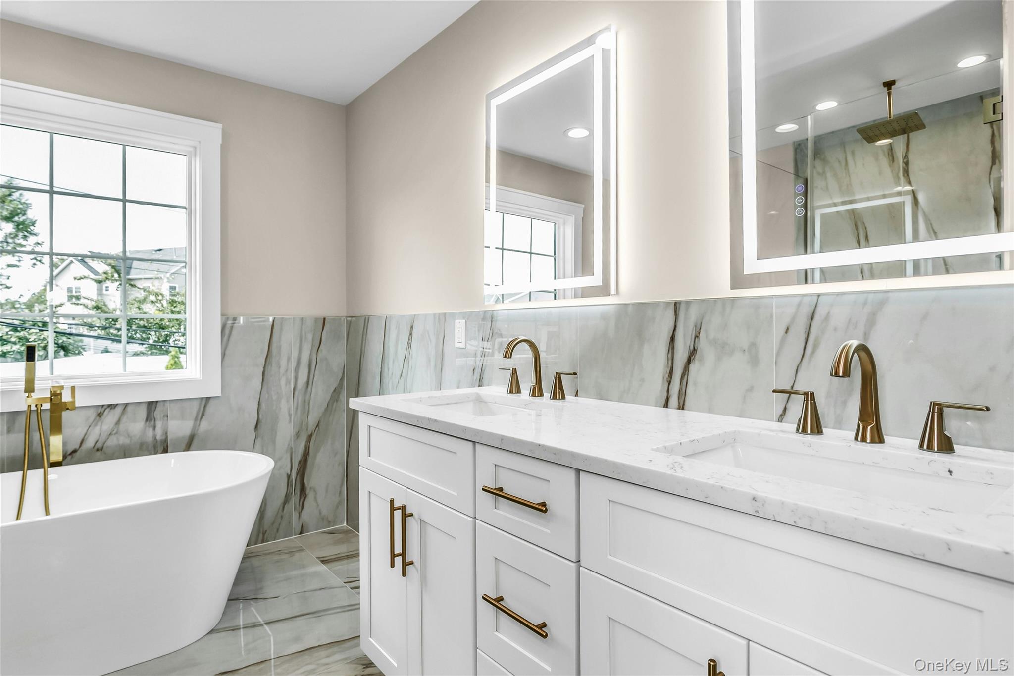 8 Sebree Place Plainview, NY 11803 - Photo 17 of 26 Full bathroom featuring a freestanding bath, tile walls, double vanity, a wainscoted wall, and a marble finish shower