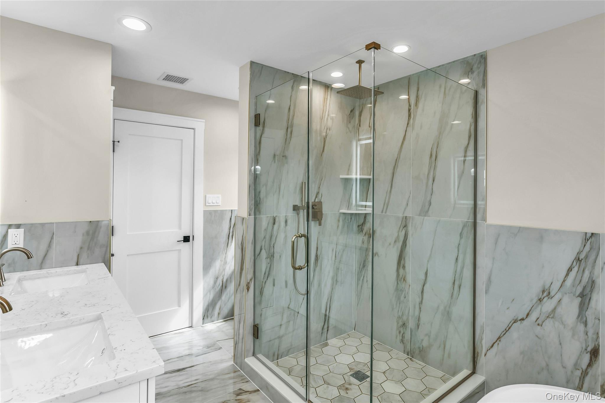 8 Sebree Place Plainview, NY 11803 - Photo 18 of 26 Bathroom with a marble finish shower, tile walls, double vanity, recessed lighting, and light marble finish flooring