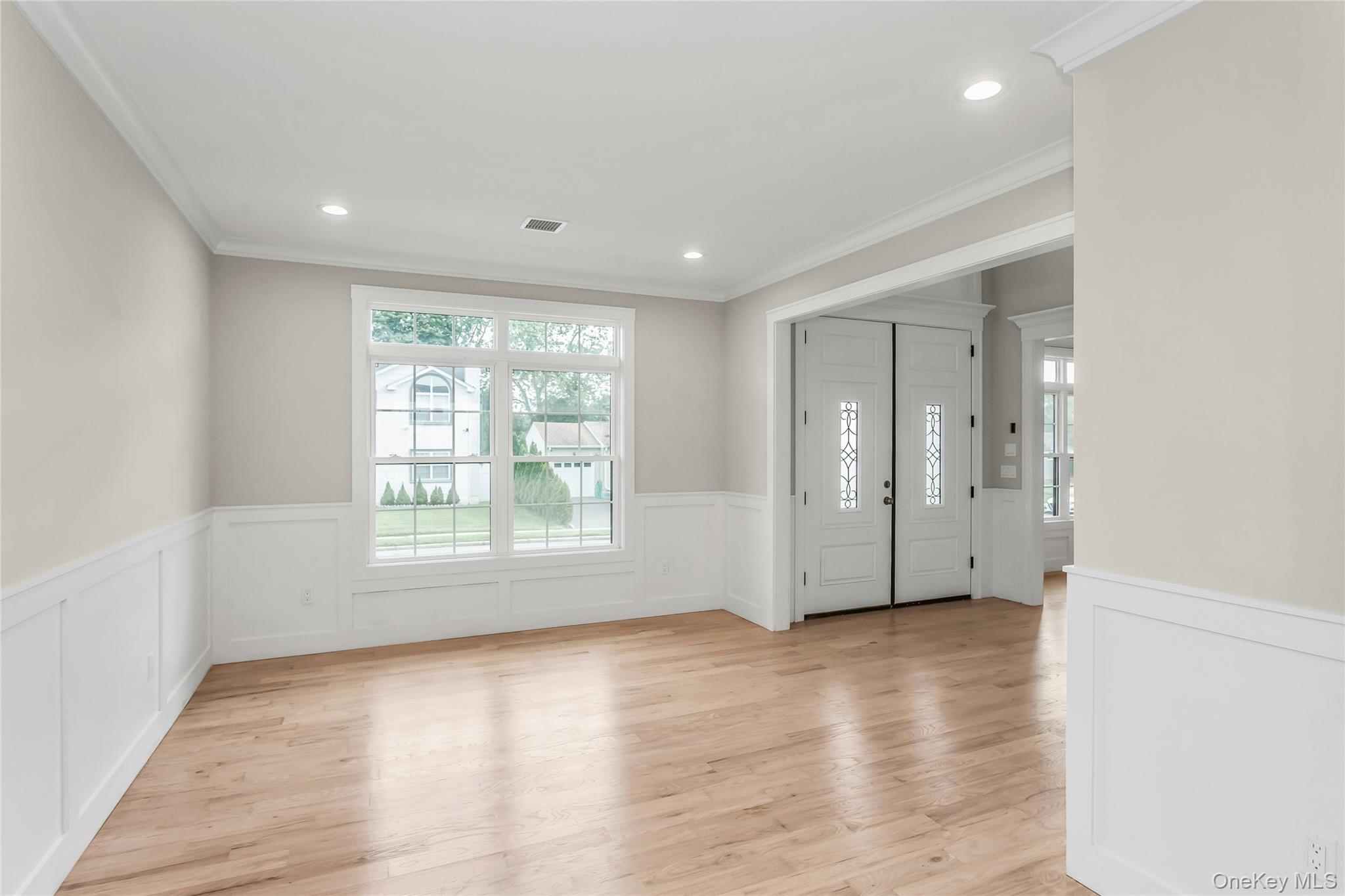 8 Sebree Place Plainview, NY 11803 - Photo 7 of 26 Foyer entrance featuring wainscoting, crown molding, light wood-style floors, a decorative wall, and recessed lighting