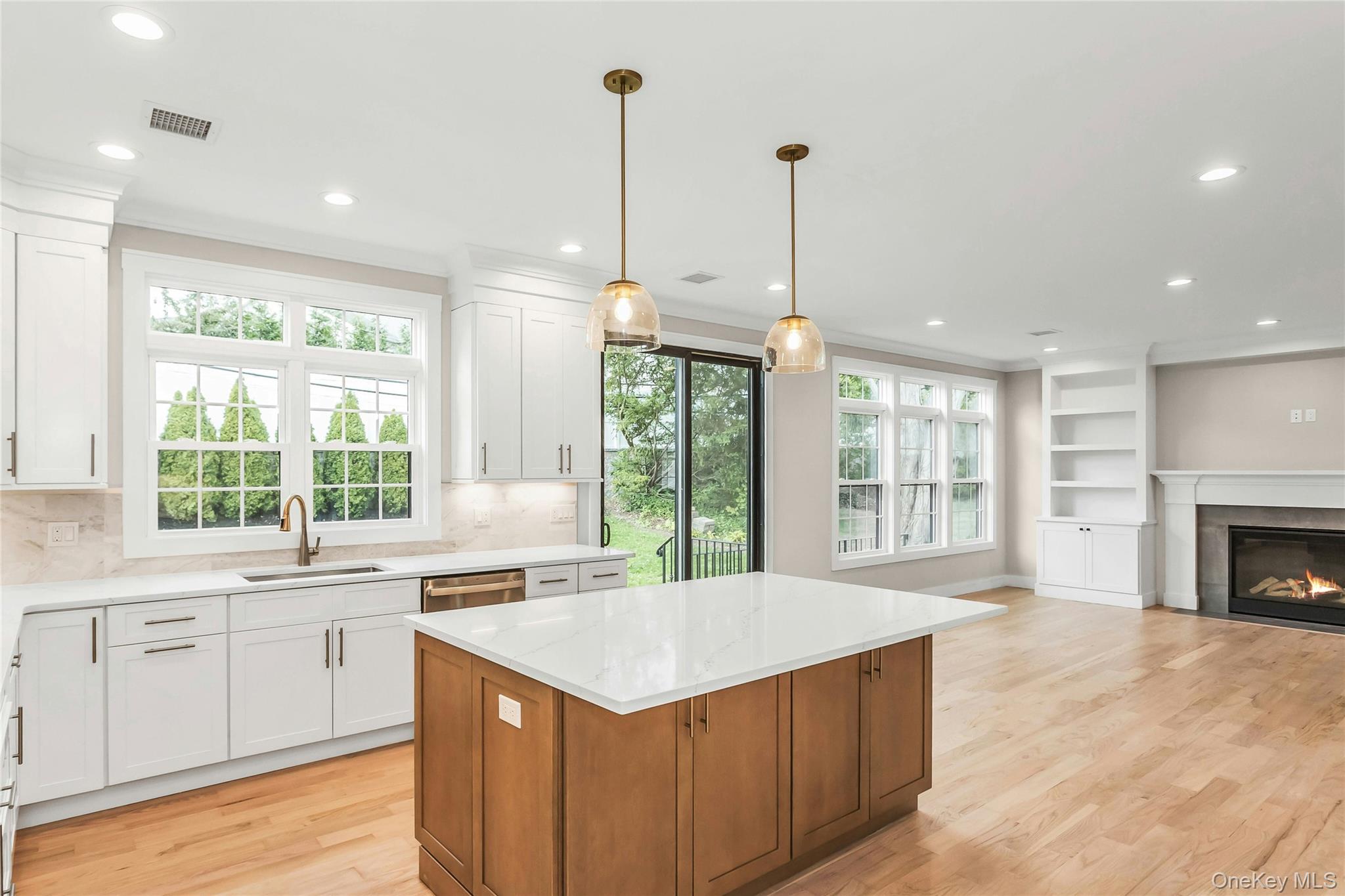 8 Sebree Place Plainview, NY 11803 - Photo 26 of 26 Kitchen featuring white cabinetry, open floor plan, brown cabinetry, light wood-type flooring, and decorative light fixtures