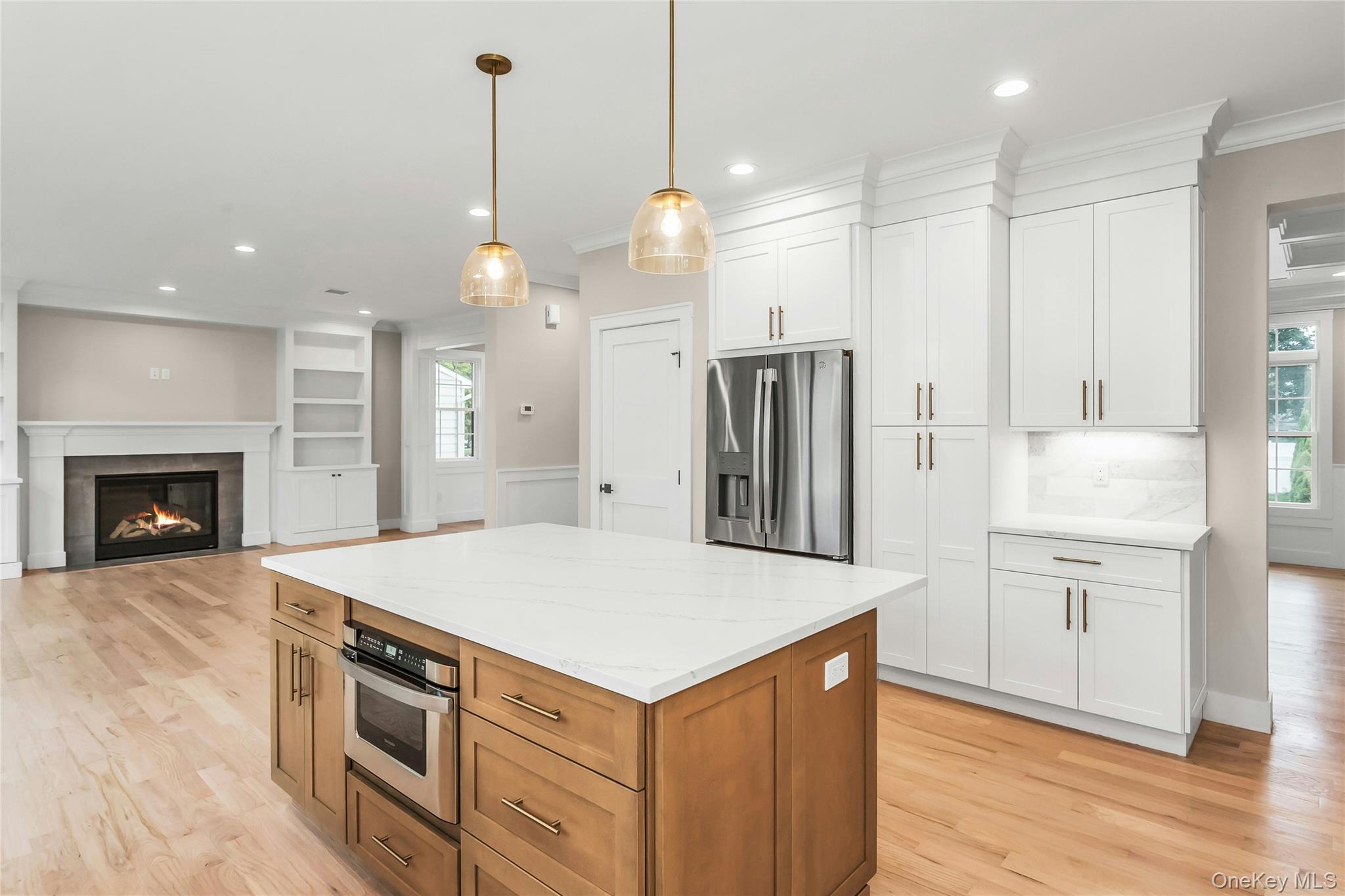 8 Sebree Place Plainview, NY 11803 - Photo 9 of 26 Kitchen with brown cabinetry, a center island, appliances with stainless steel finishes, decorative light fixtures, and white cabinetry