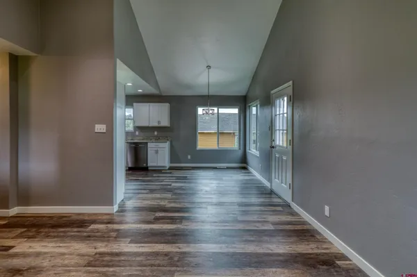 a view of a hallway with wooden floor and a kitchen