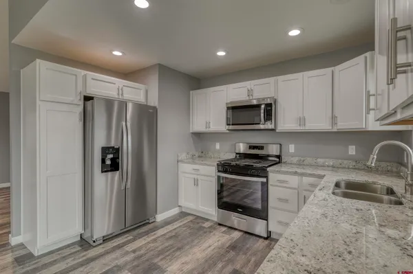 a kitchen with stainless steel appliances granite countertop a refrigerator stove and sink