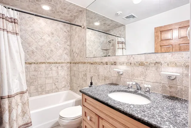a bathroom with a granite countertop sink toilet and bathtub