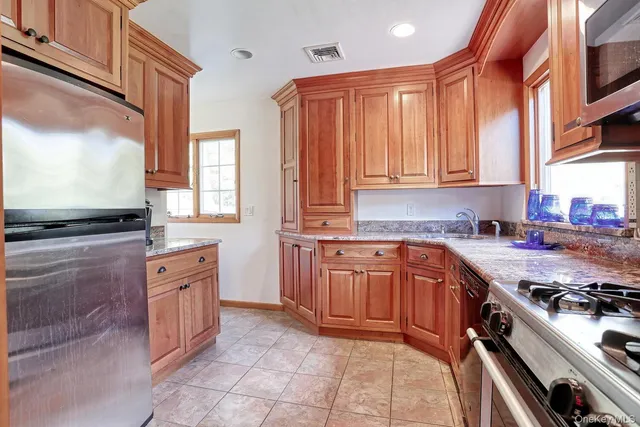 a kitchen with stainless steel appliances granite countertop a stove a sink and a microwave