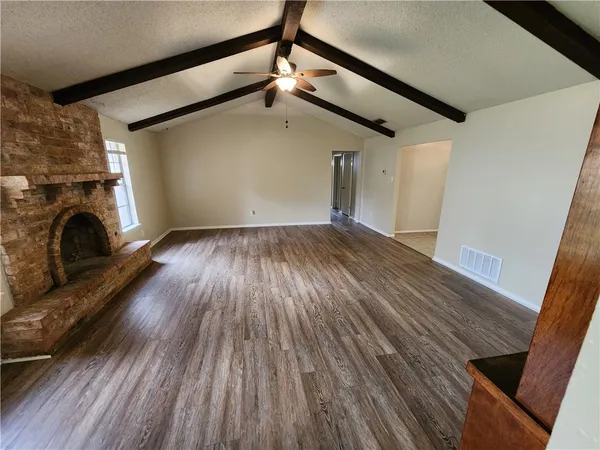 a view of empty room with wooden floor and fireplace