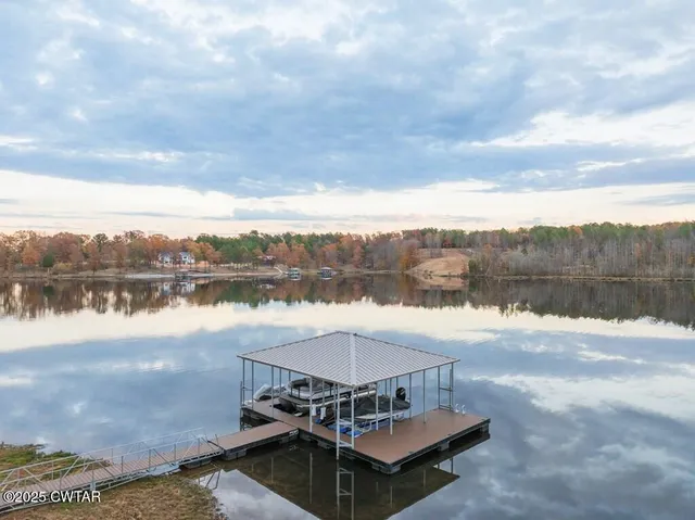 a view of a livingroom with a fireplace large windows and a ceiling fan