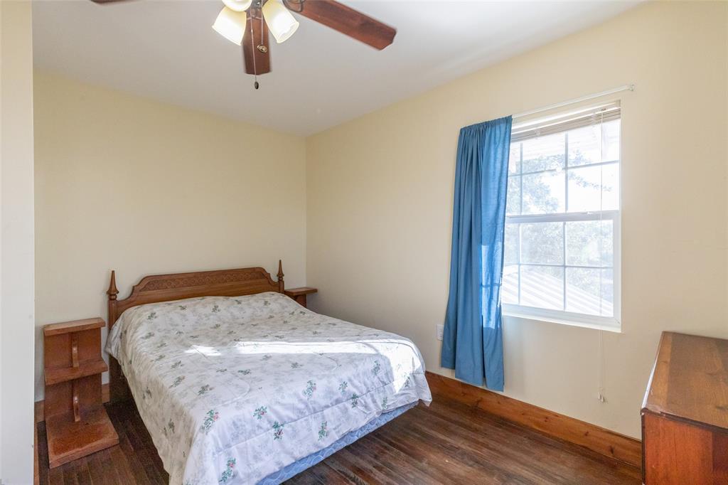 640 Ground Street Moran, TX 76464 - Photo 27 of 35 Bedroom featuring wood-finish flooring, a ceiling fan with integrated lighting, and a window providing natural illumination