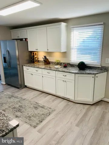 a kitchen with stainless steel appliances granite countertop a sink a stove a refrigerator a microwave oven with white cabinets