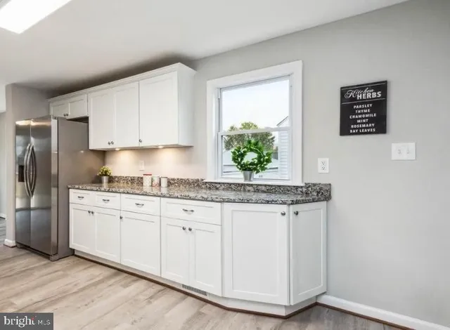 a kitchen with granite countertop a stove a sink and a refrigerator