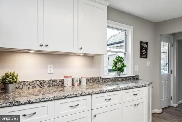 a kitchen with granite countertop white cabinets and a window