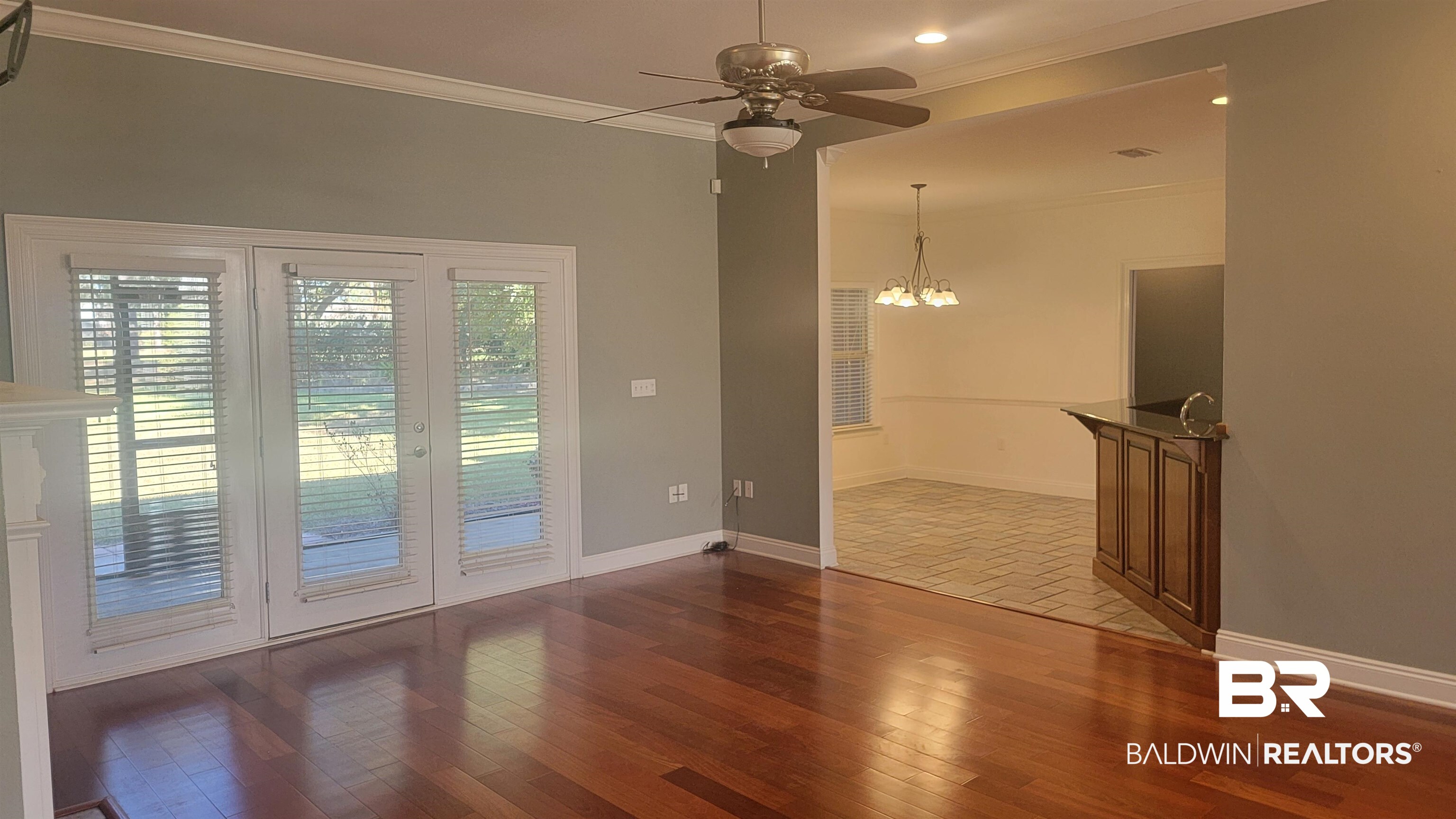 306 South Tee Drive Fairhope, AL 36532 - Photo 12 of 37 Spare room with crown molding, ceiling fan with notable chandelier, and dark hardwood / wood-style floors