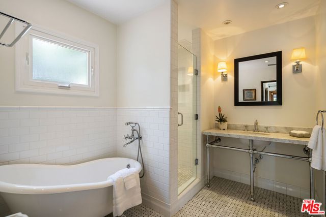 a bathroom with a tub a sink and mirror